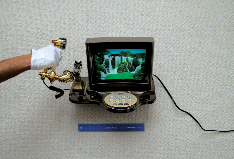 A photograph of a retro looking telephone being measured by a ruler.