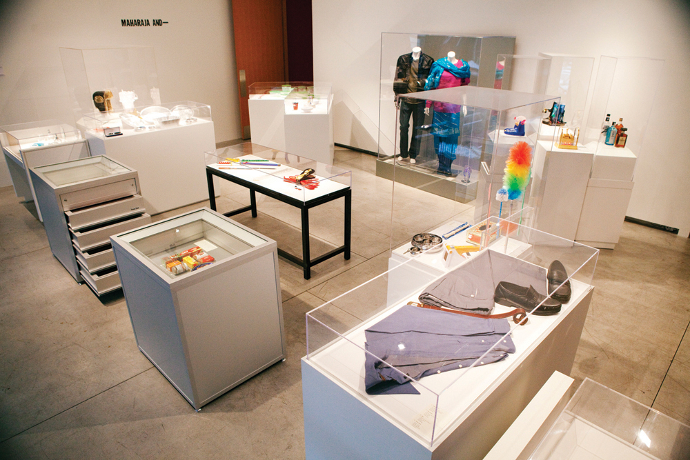 A collection of various plinths with plexiglass display cases on top containing a variety of everyday objects.