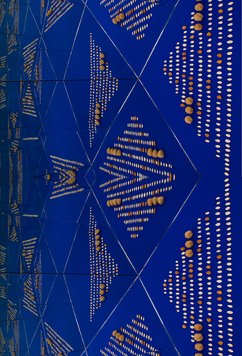 A blue display case with mirrored walls creating an optical illusion of the neatly arranged seeds and nuts inside of it.