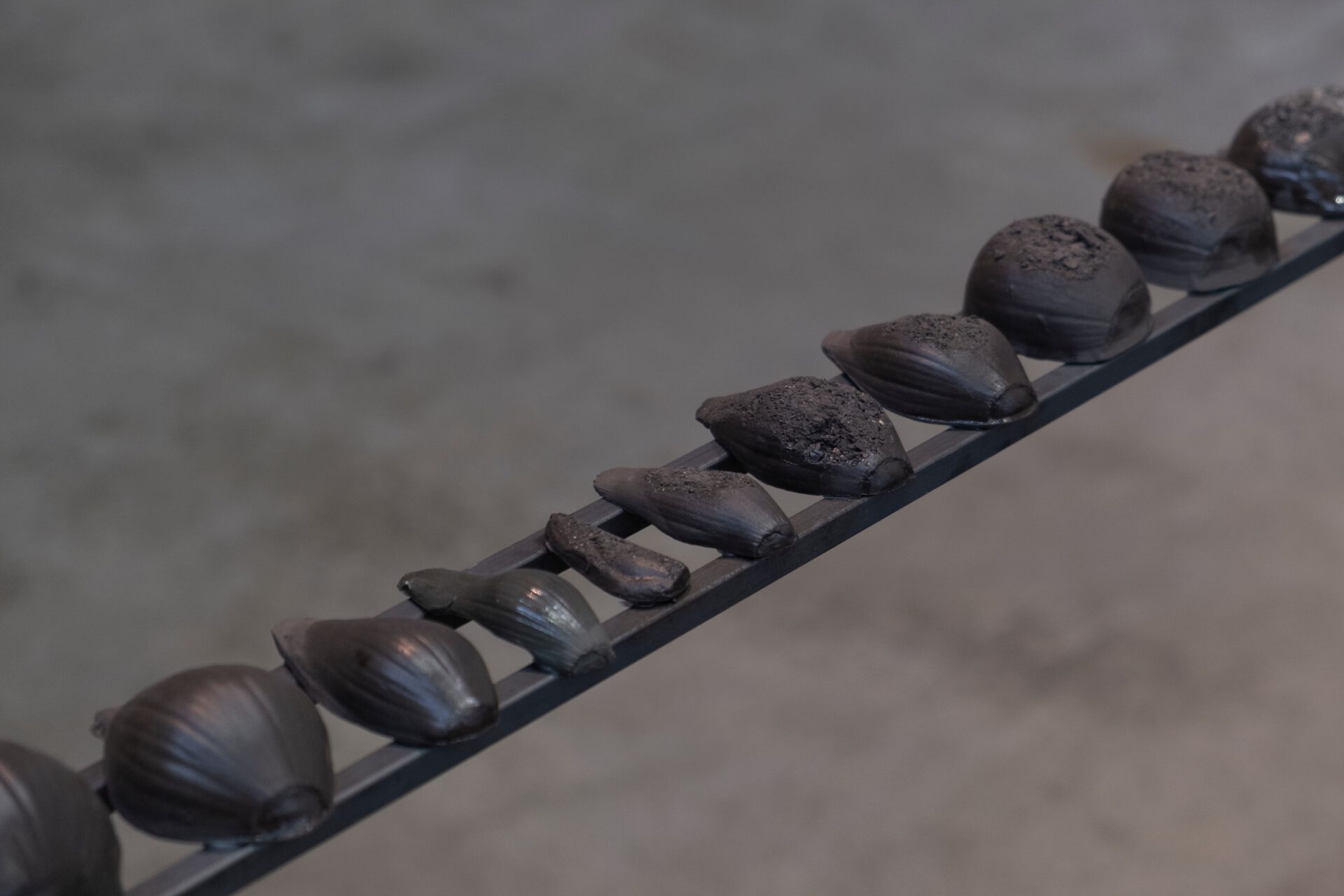 Close up of various shaped ceramic onions lined on steel poles.