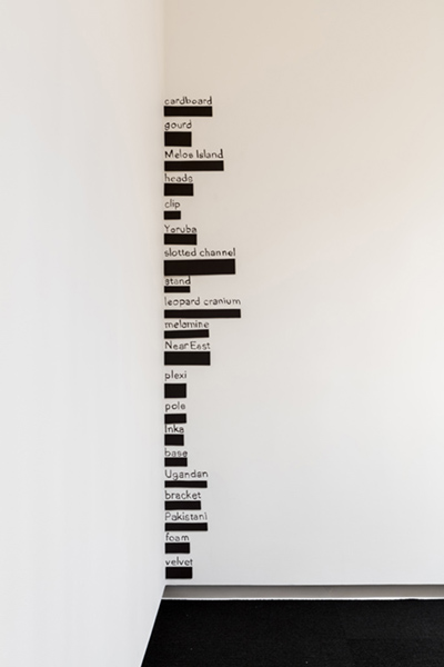 Black text hand written in the corner of a white wall, one word per line and divided by thick black bars.