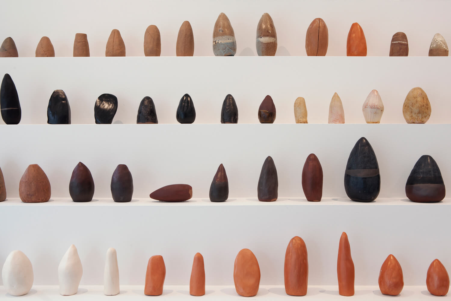 Four step plinth containing a series of earth toned sculptures.