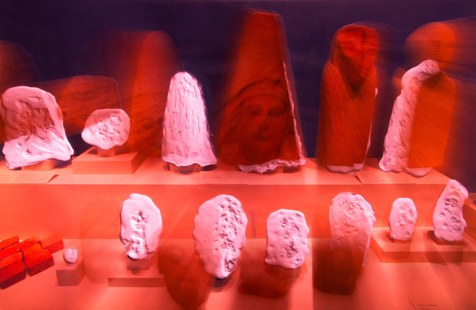 Sculptures of various sizes lined up on a two level plinth.