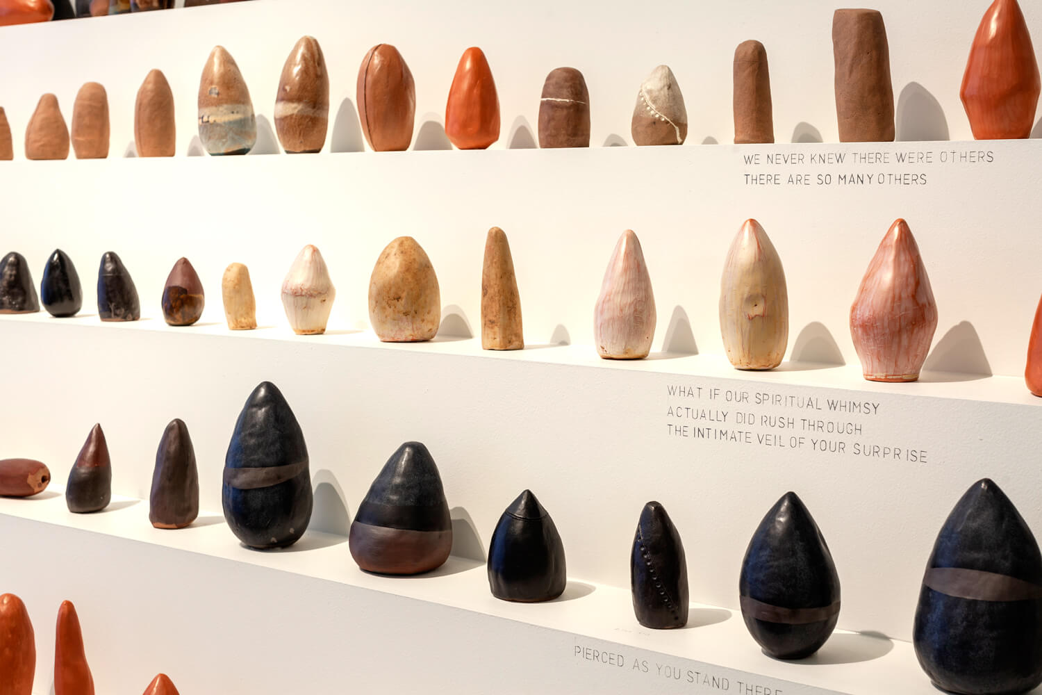 A cropped image of various sculptures lined up on a 5 level plinth.