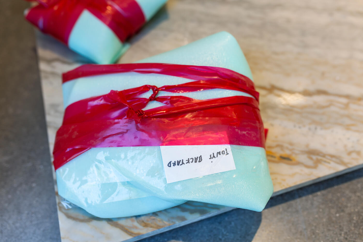 Wrapped small sculpture with a note attached to it reading "TONY'S BACKYARD".