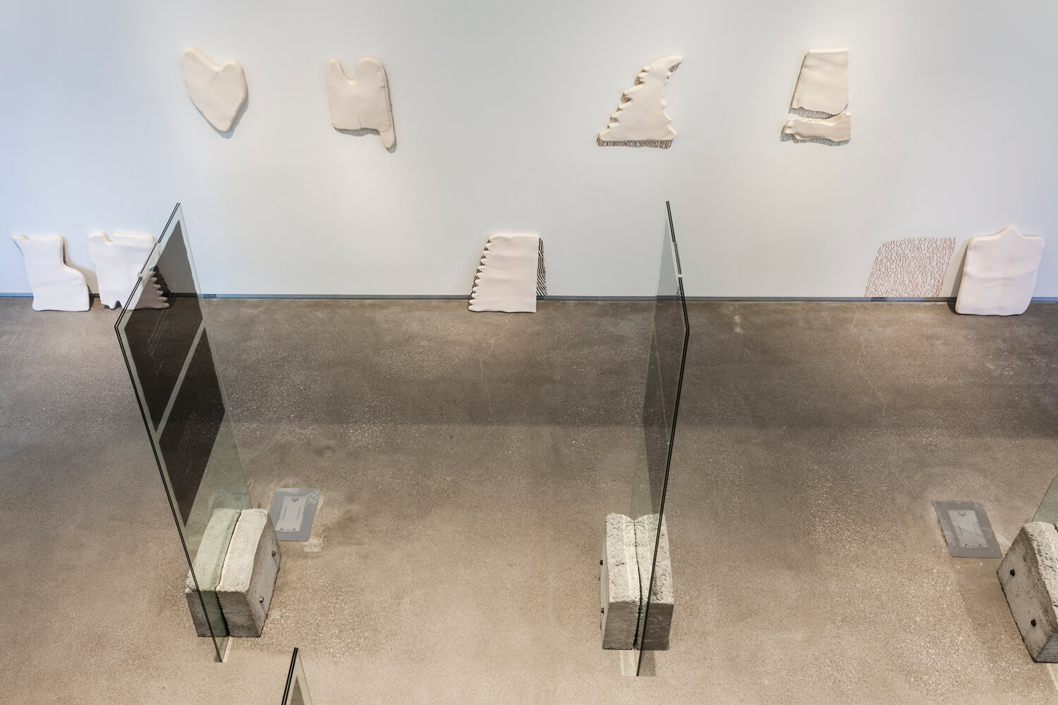 Gallery room filled with tablet sculptures on the ground and hanging on the wall.