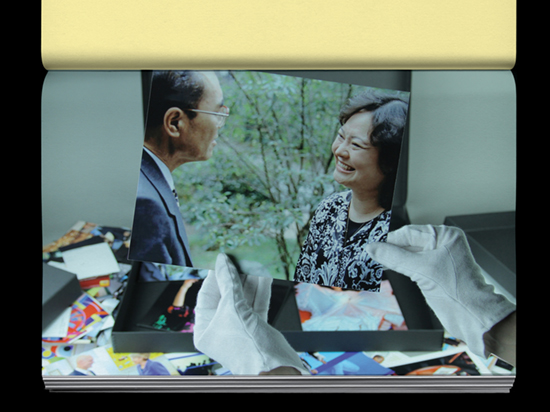 Hands wearing white archive gloves holding a photograph of two people interacting.